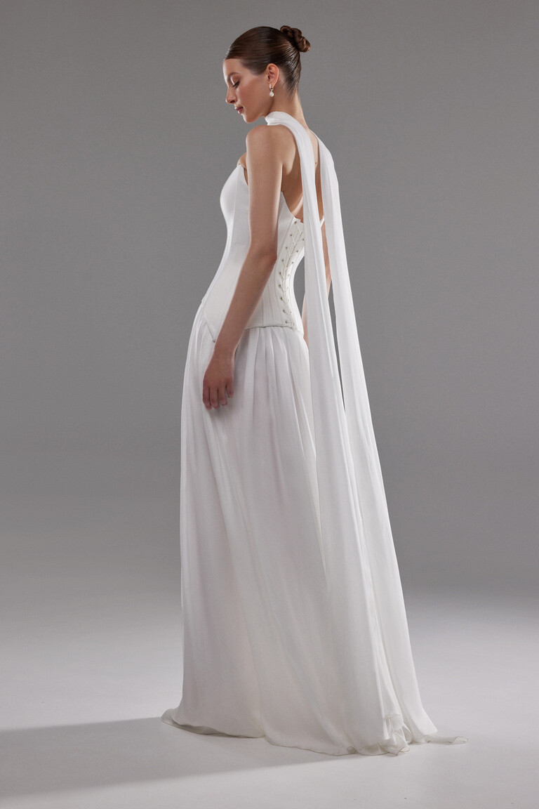 Side profile of Artemide gown showing lace-up corset detail and long fabric streamers
