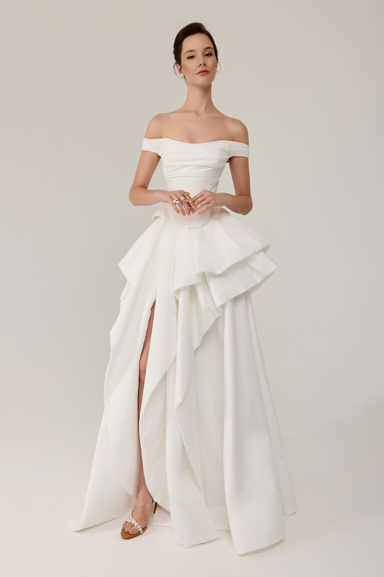 Alana corset wedding dress front view featuring draped sleeves and voluminous tiered skirt in off-white
