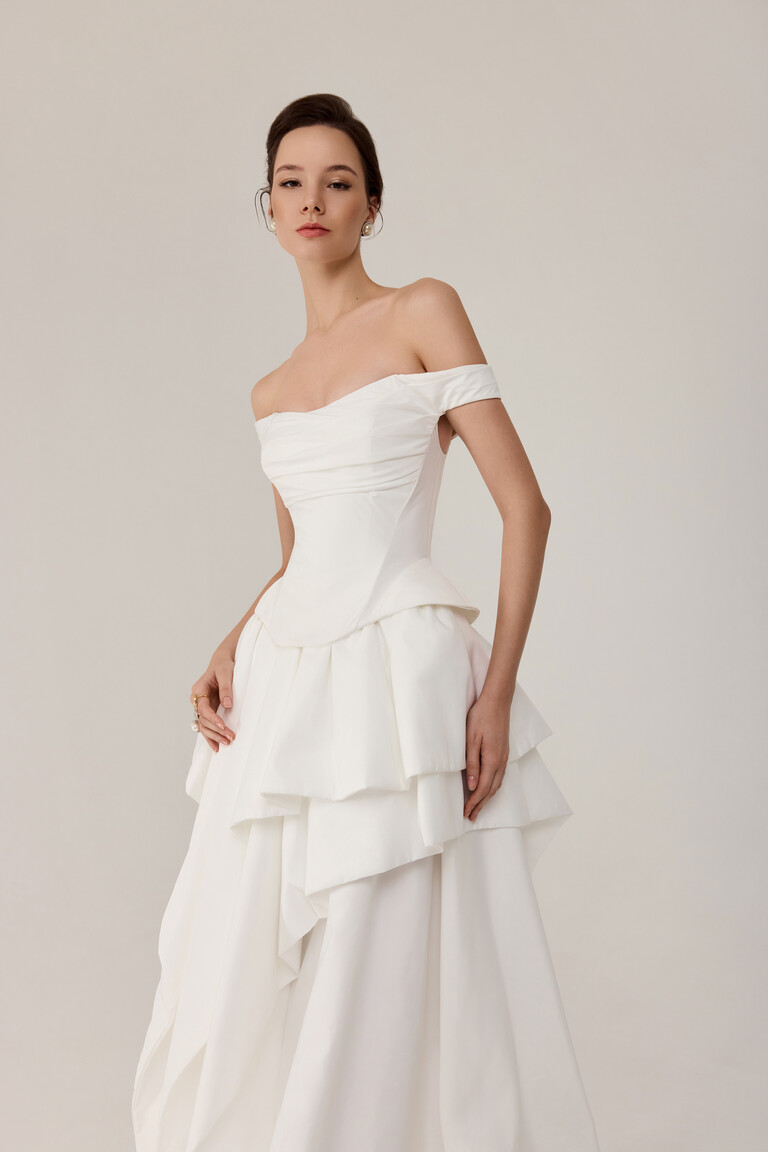 Side angle of Unona Alana off-white gown showing architectural silhouette and asymmetrical tiers