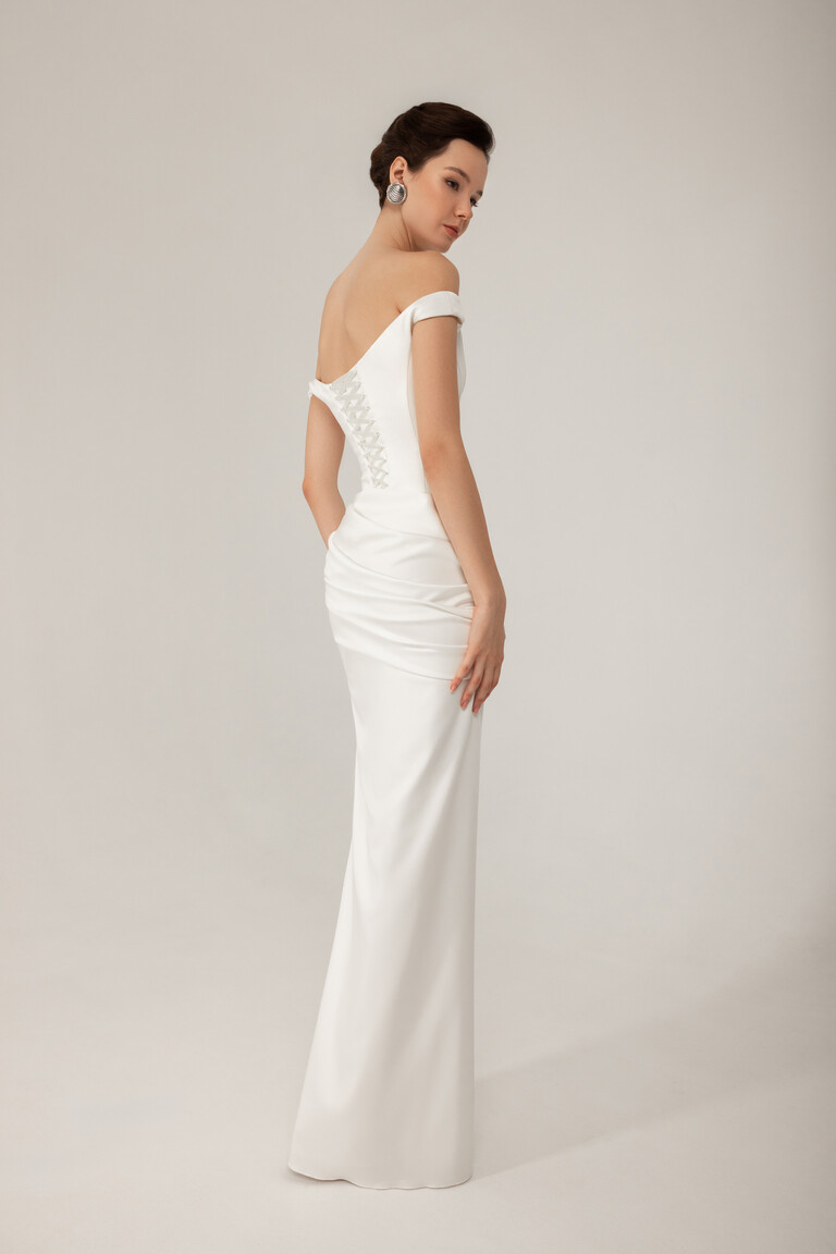 Three quarter back view of Kaira sheath wedding dress showing fitted silhouette and sleeves