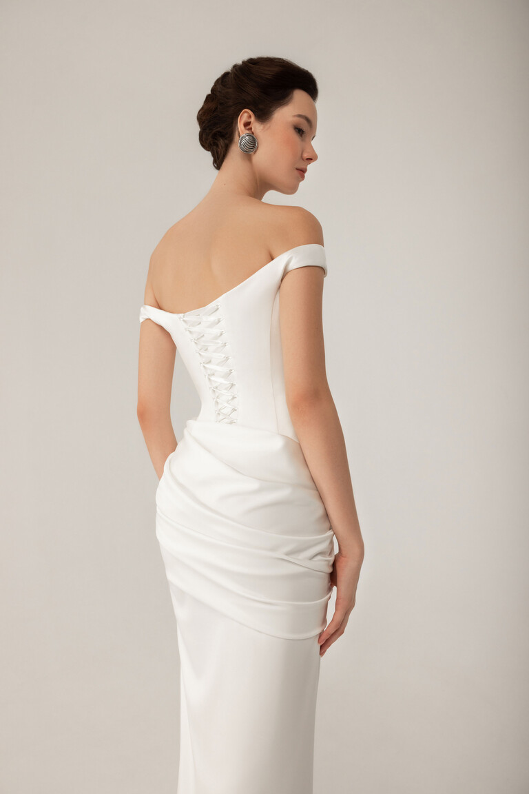 Back view of Kaira ivory satin dress featuring lace-up corset closure and hip draping