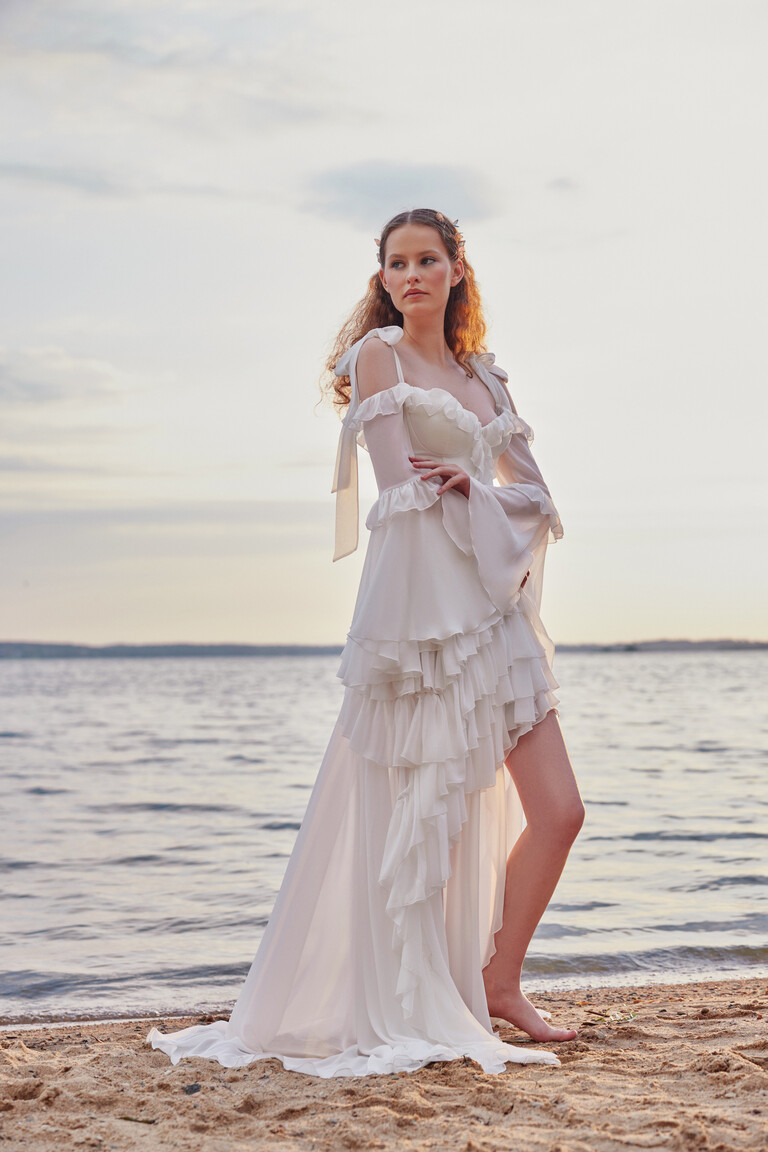 Riot chiffon bridal gown on beach featuring cascading ruffles and long flowy train