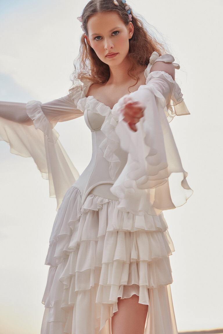 Low angle view of Riot off-white dress highlighting translucent chiffon layers and leg slit