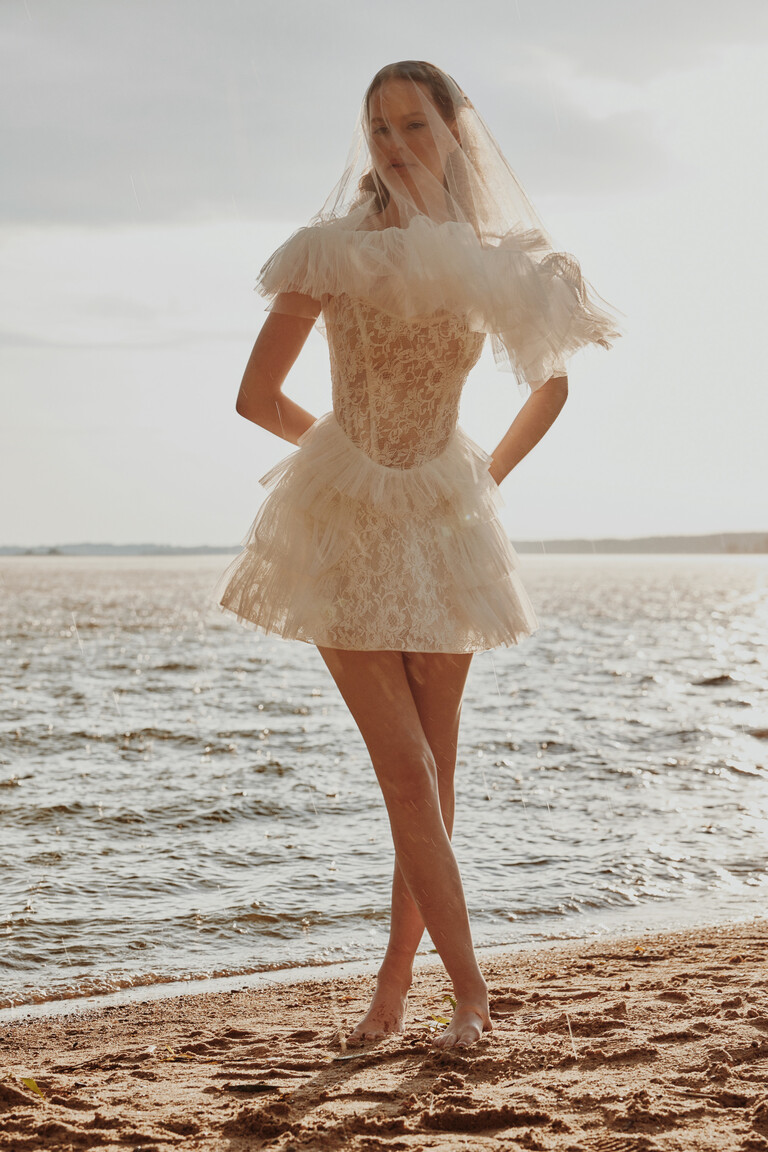 Unona Luna mini bridal gown worn with veil on a sandy beach