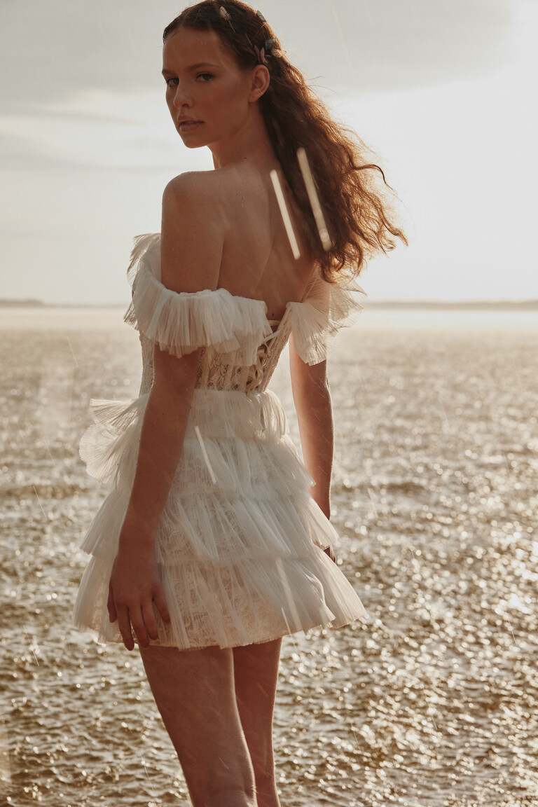 Rear angle of Luna short engagement dress showing corset lacing by the sea