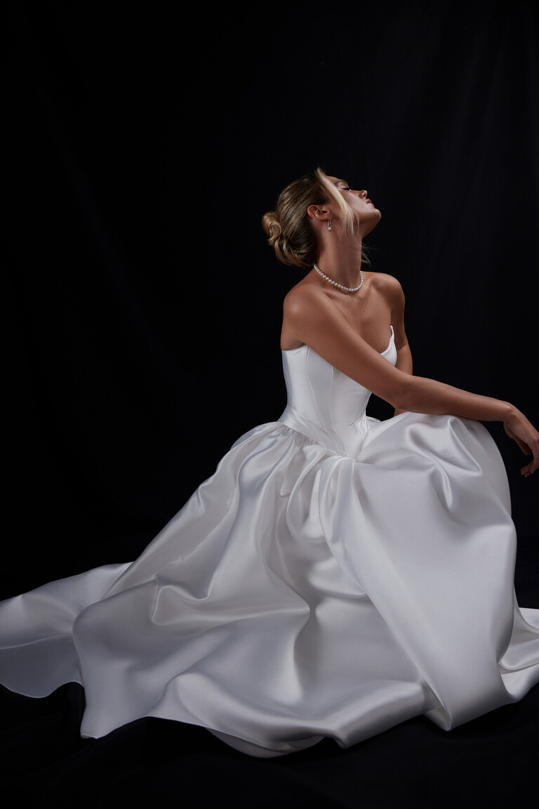 Side profile of seated bride in Faith voluminous Mikado wedding gown
