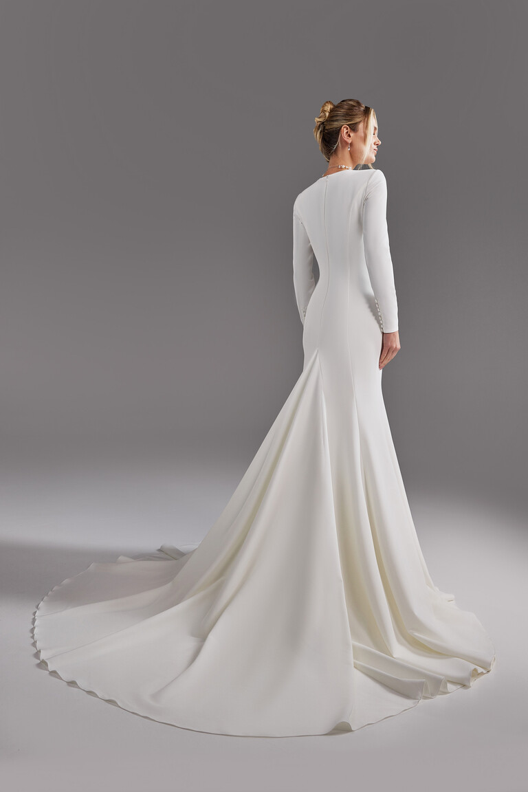 Back view of Odetta modest wedding gown with long train and buttoned sleeve details