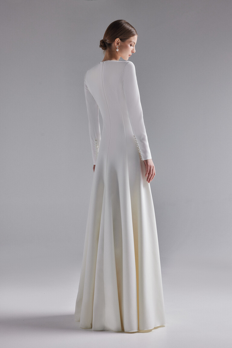 Side profile of Stella ivory gown featuring sleeve buttons and flared skirt