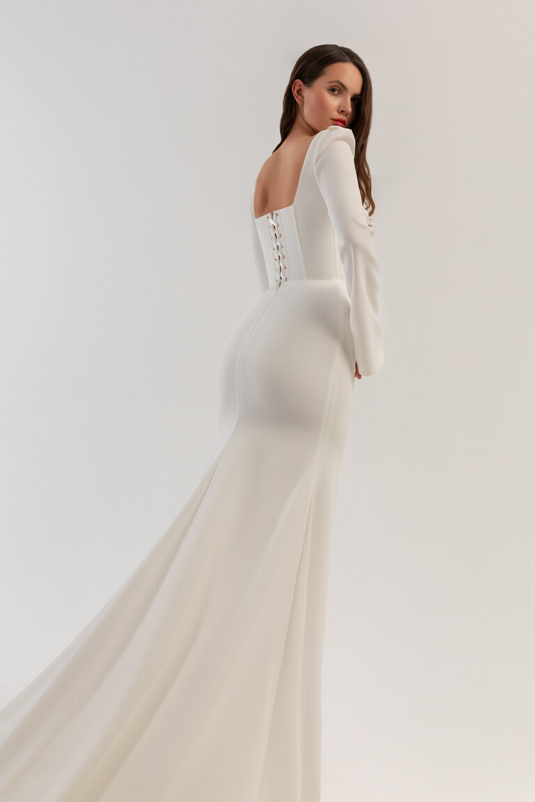Roksolana fitted mermaid dress featuring a lace-up back and sweeping train Back view of Roksolana ivory crepe wedding gown showing lace-up corset and mermaid train