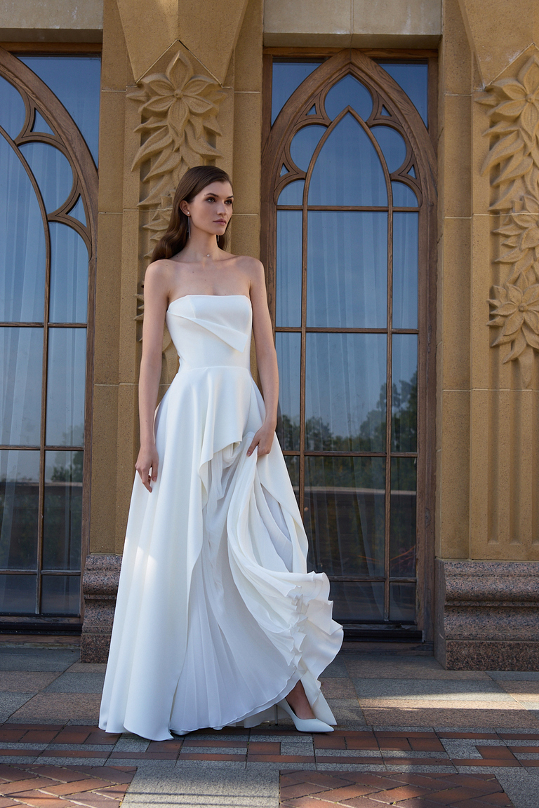 Leyana Strapless Crepe Gown Front View Front view of Leyana crepe wedding gown featuring structured bodice and pleated skirt insert