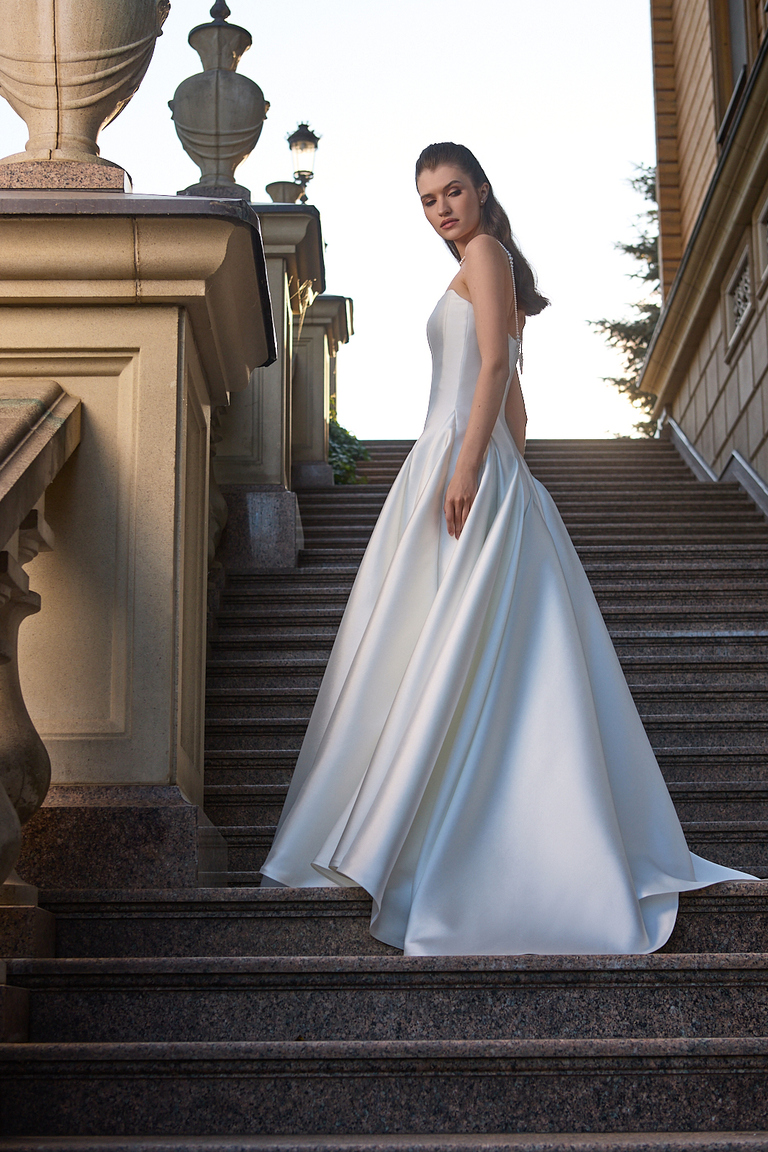 Side profile of Alviya Mikado wedding dress displaying A-line silhouette and fitted bodice on stairs
