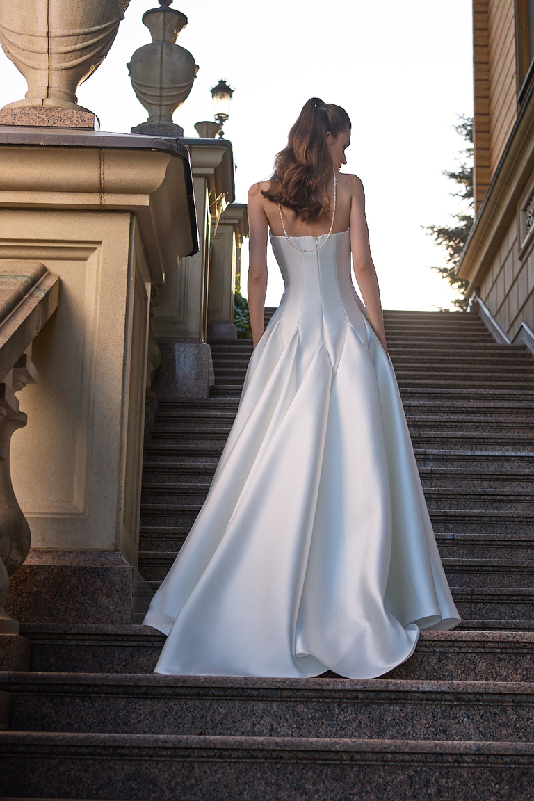 Back view of Alviya bridal gown showing open back design with pearl accents and pleated Mikado skirt