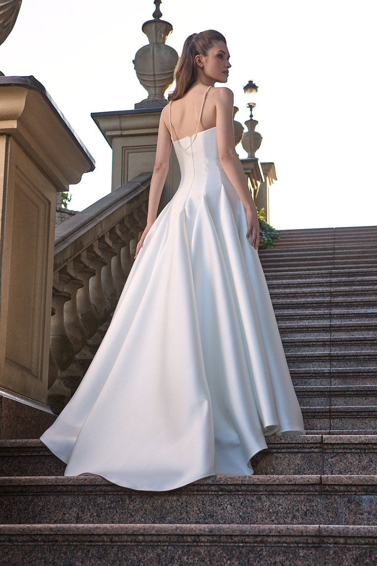 Low angle back view of Alviya dress featuring low back with draped pearl beads and structured fabric