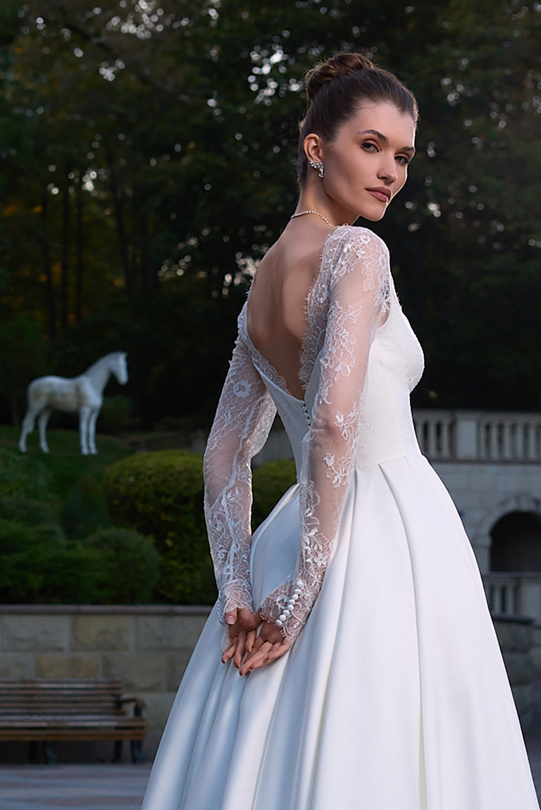 Rear side view of Quinn bridal gown featuring open back and buttons on lace sleeves