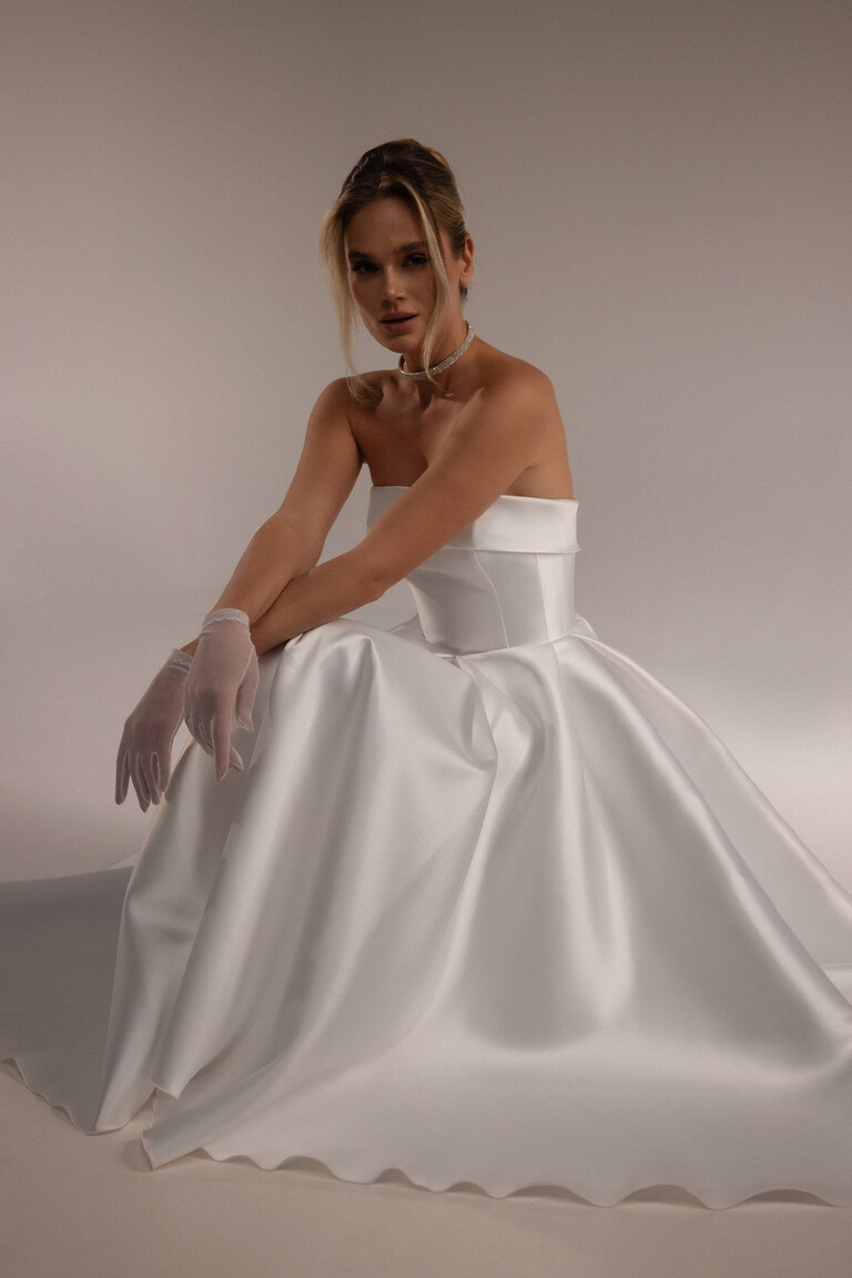 Luxurious Mikado Fabric Detail on Seated Bride Seated bride in Sophie Midi ivory Mikado dress showing voluminous A-line skirt and strapless bodice