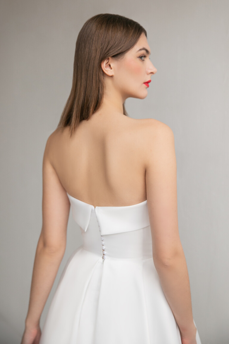Back bodice view of Sophie ivory dress with folded top edge and center button closure