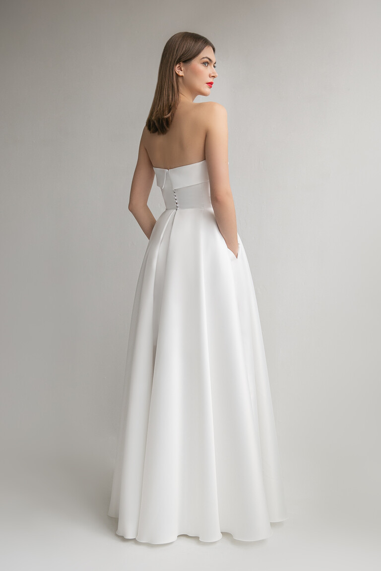 Full length back view of Sophie A-line wedding dress with hands in side pockets and button details