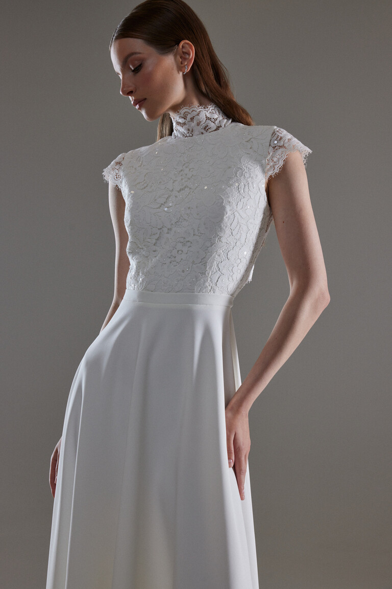 Detailed View of Floral Lace Bodice and Cap Sleeves Close up of Anabel bridal gown lace bodice with high neck cap sleeves and delicate sequin details