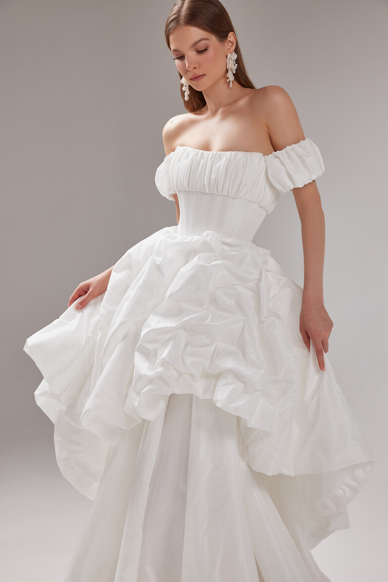 Three-quarter view of the Unona Savannah ball gown in ivory with detachable off-the-shoulder puff sleeves and a structured corset.