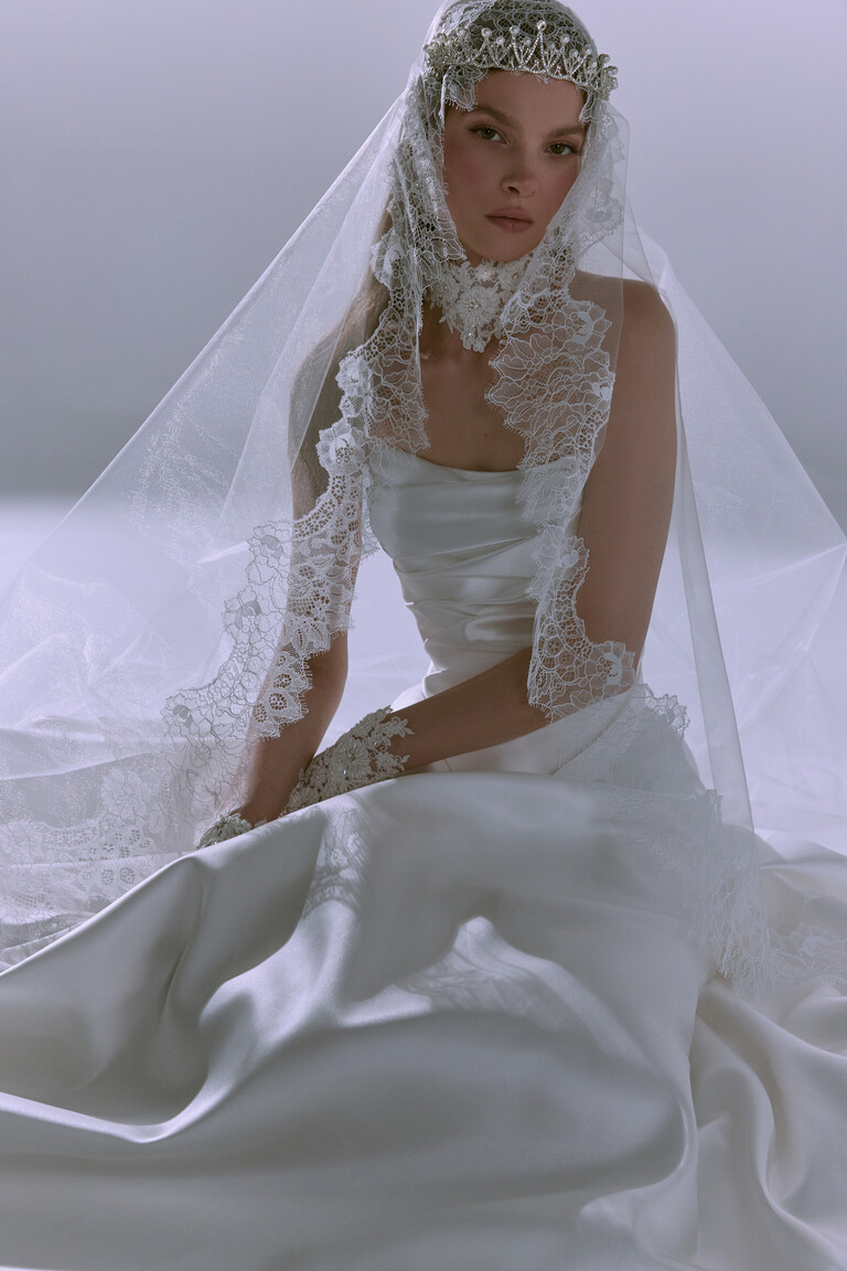 Ivory sheer tulle wedding veil Tori with broad scalloped lace border seated pose