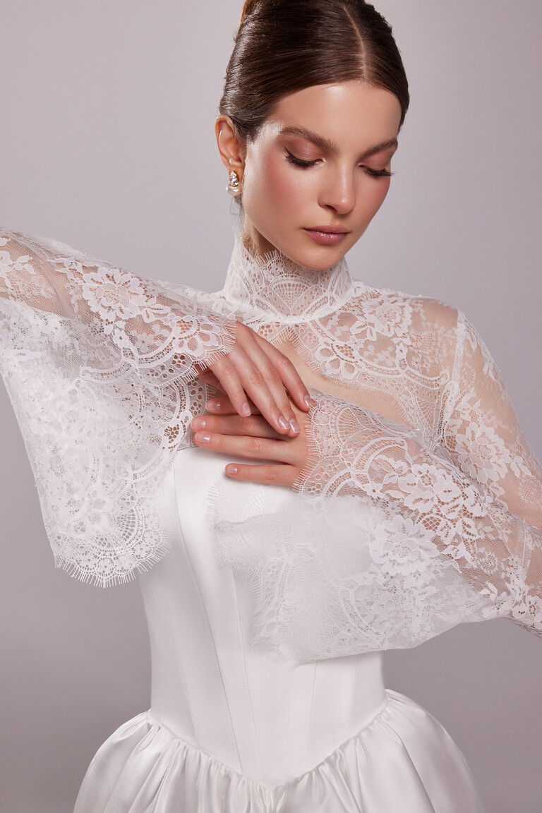 Close-up of the Unona Tessa Bolero's high stand-up collar and long sleeves in sheer ivory lace with delicate eyelash trim.