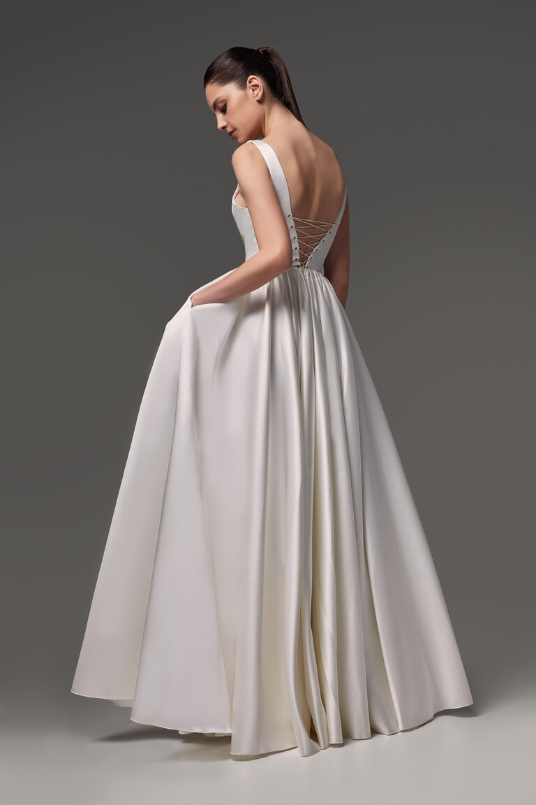 Unona Barbara A-line wedding dress in ivory satin from the back three-quarter angle showing the corset detail and side pocket.