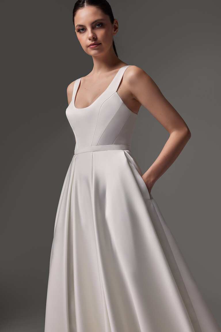 Model in a three-quarter view of the Barbara midi ivory dress, turning to show the A-line skirt flow and side pocket detail.