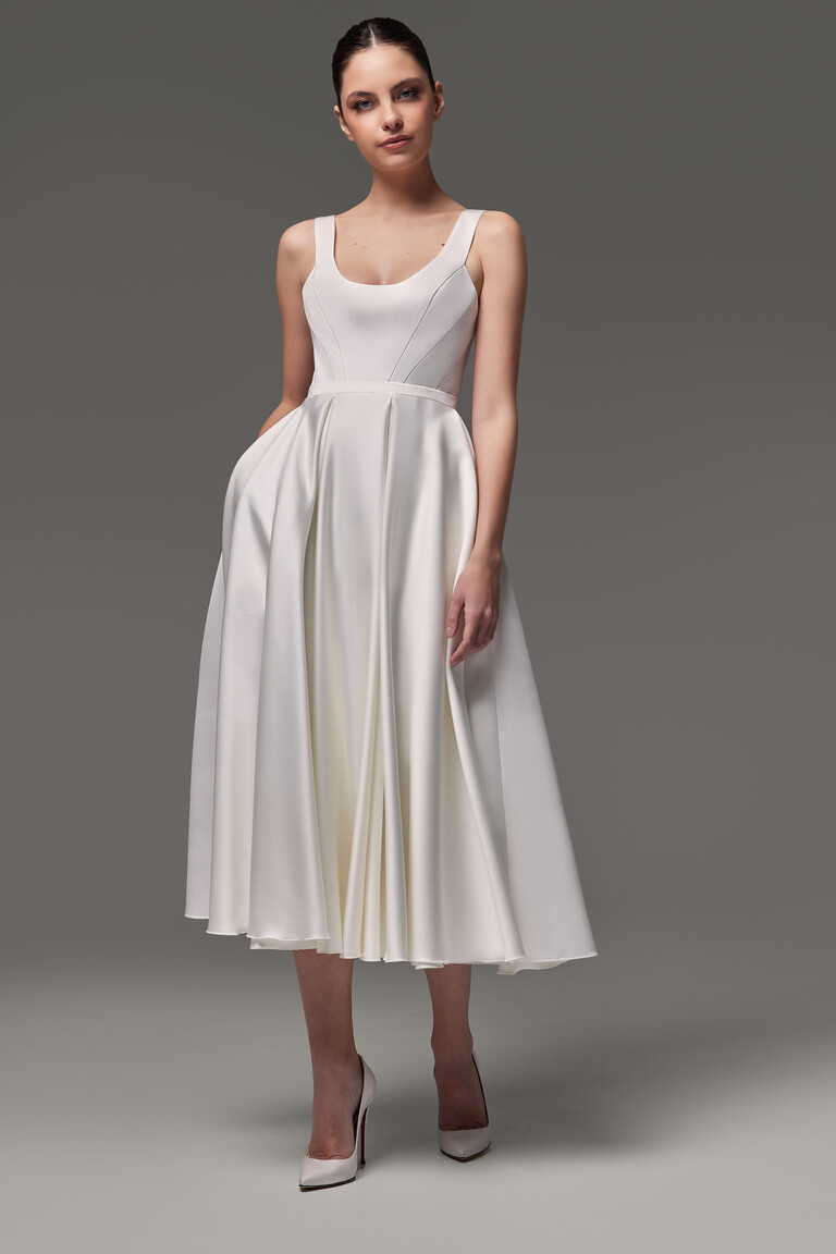 Full front view of the Barbara midi tea-length dress in ivory satin, featuring a pleated A-line skirt and scoop neckline.