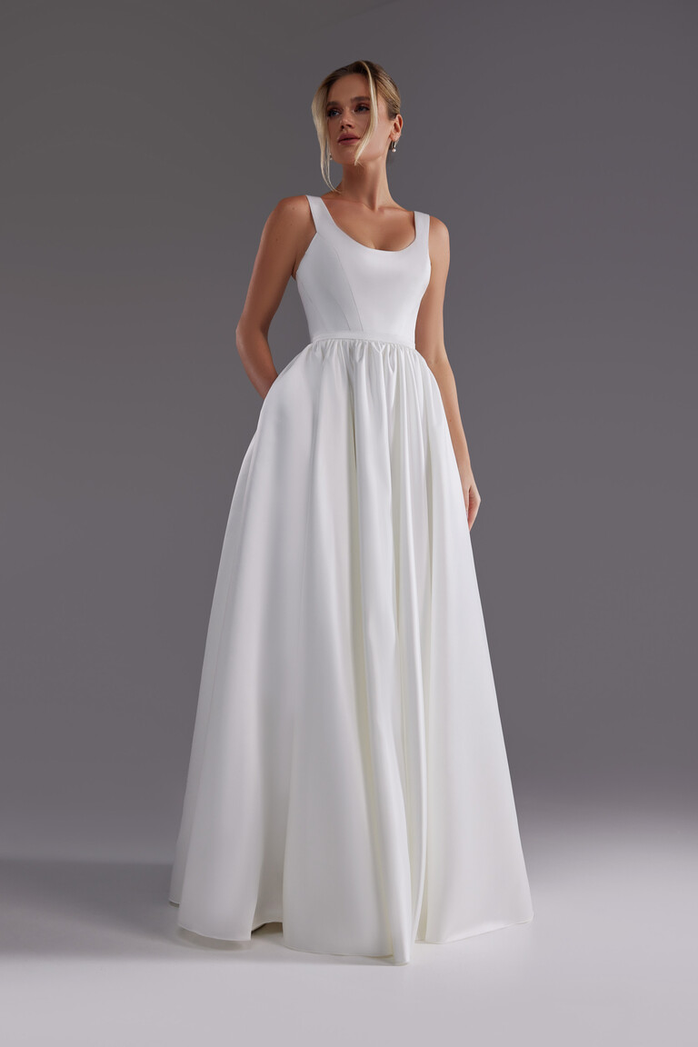 Front view of the Unona Barbara ivory satin dress highlighting the structured bodice with seams and A-line skirt with pockets.