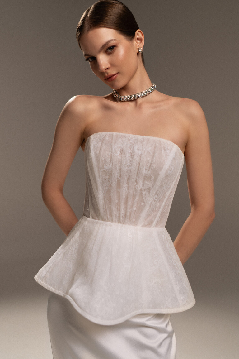 Intricate Lace Corset & Peplum Detail | Unona Alicia Gown Close-up of the Alicia wedding dress bodice showing the detailed strapless lace corset with boning and the structured peplum waist.