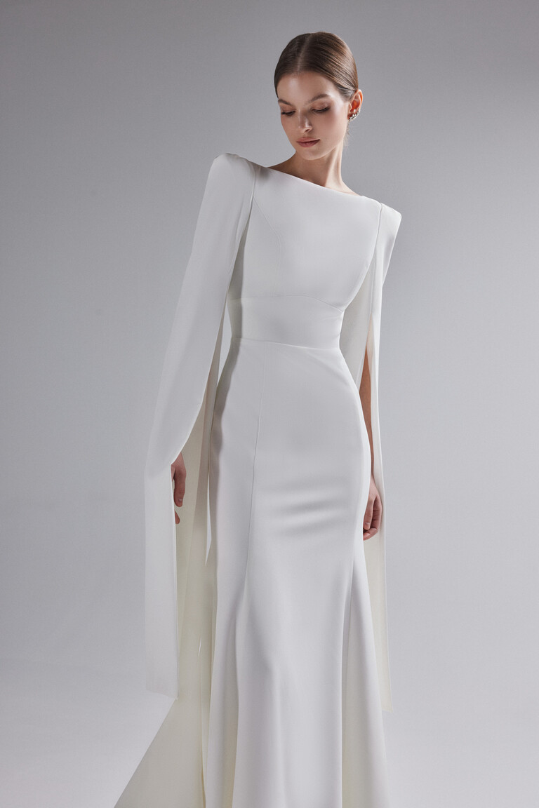 Fitted mermaid silhouette of Ashley wedding gown showing structured shoulders and cape sleeves