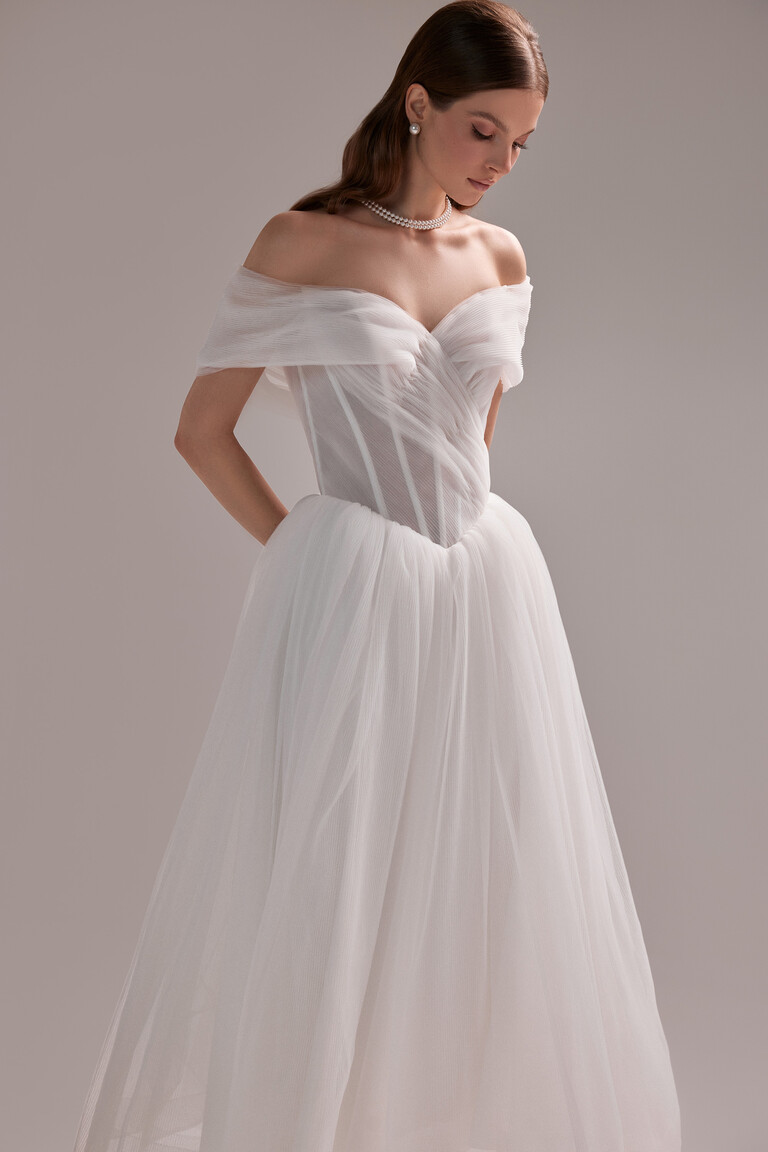 Unona Tutu Midi wedding dress three-quarter view. A-line pleated tulle gown with a romantic off-the-shoulder corset bodice.