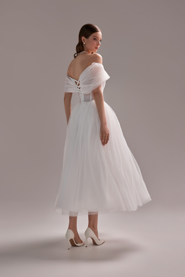 Full back view of the Unona Tutu Midi ivory dress. Highlighting the lace-up corset and flowy tea-length pleated tulle skirt.