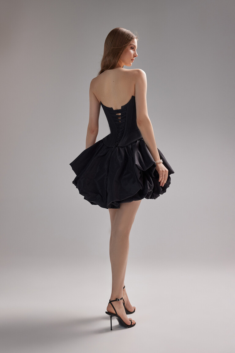 Back view of the Unona Amira Mini black dress showcasing the adjustable lace-up corset back and dramatic bubble hem skirt