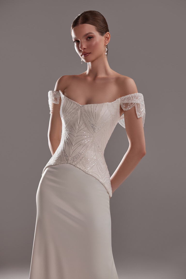 Intricate Lace Corset Front View Front view of Diva wedding dress corset featuring intricate geometric lace and draped wing sleeves