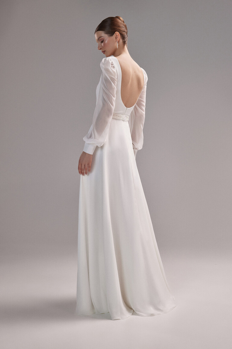 Back view of the Unona Rita long sleeve wedding dress in ivory highlighting the deep U-shaped open back and flowing crepe skirt.