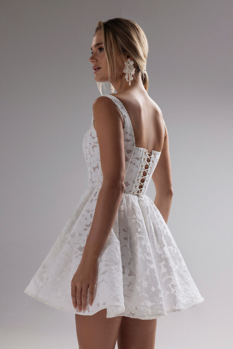 Rear side view of Ruta mini dress showing lace-up corset back and flared floral lace skirt