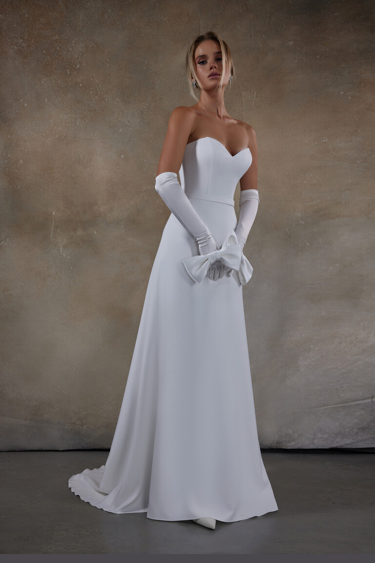 Adeline fit-and-flare bridal gown with model holding large white bow accessory