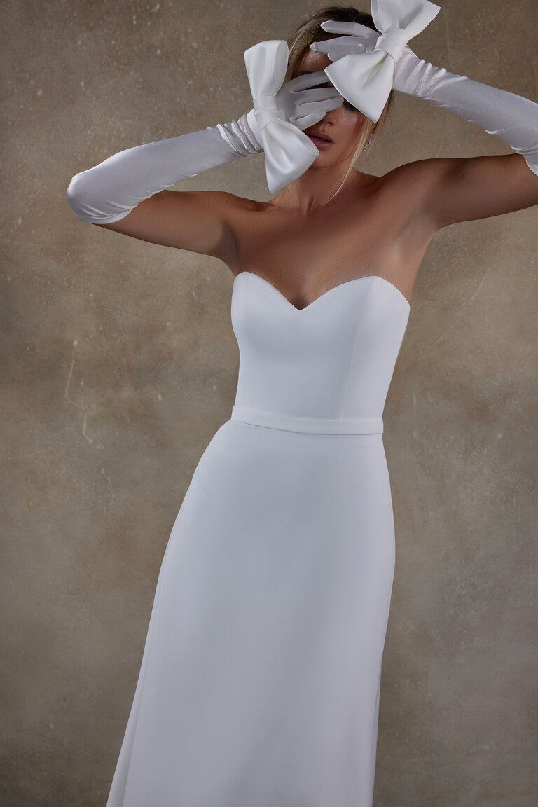Artistic shot of Adeline wedding dress with model hiding face behind bow gloves
