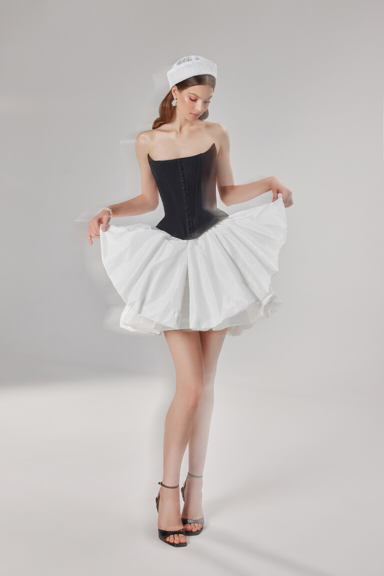 Model wearing the Amira Mini black corset dress with ivory skirt for a chic and minimalist party look