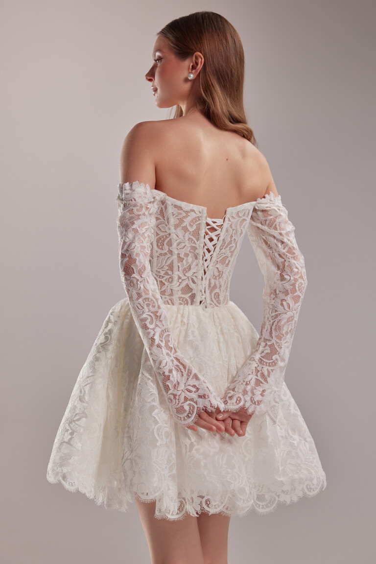 Back three-quarter view of the Eden short wedding dress showing the elegant corset lace-up closure and off-the-shoulder sleeves.