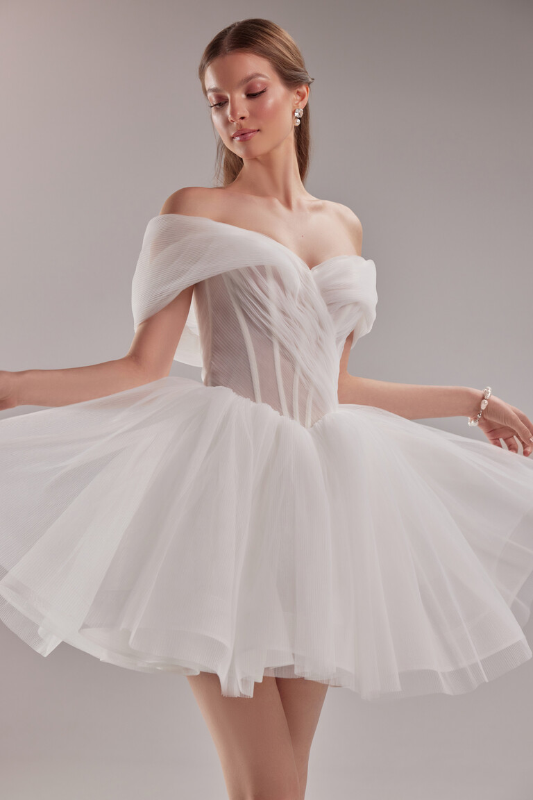 Three-quarter view of the Tutu mini ivory dress showing the pleated tulle draped corset and romantic off-the-shoulder straps.