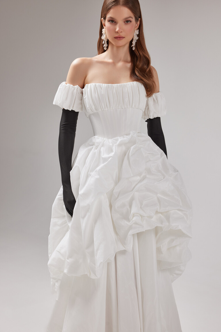 A modern styled look of the Unona Savannah gown featuring off-the-shoulder puff sleeves and a structured boned taffeta bodice.