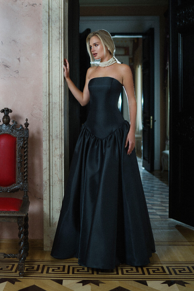 Unona Francesca black strapless ball gown full front view showcasing the drop waist and voluminous satin skirt in a classic setting.