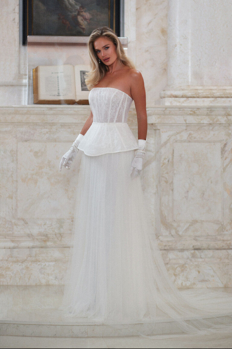 Alla wedding dress front view with gloves, lace corset, and peplum in marble interior