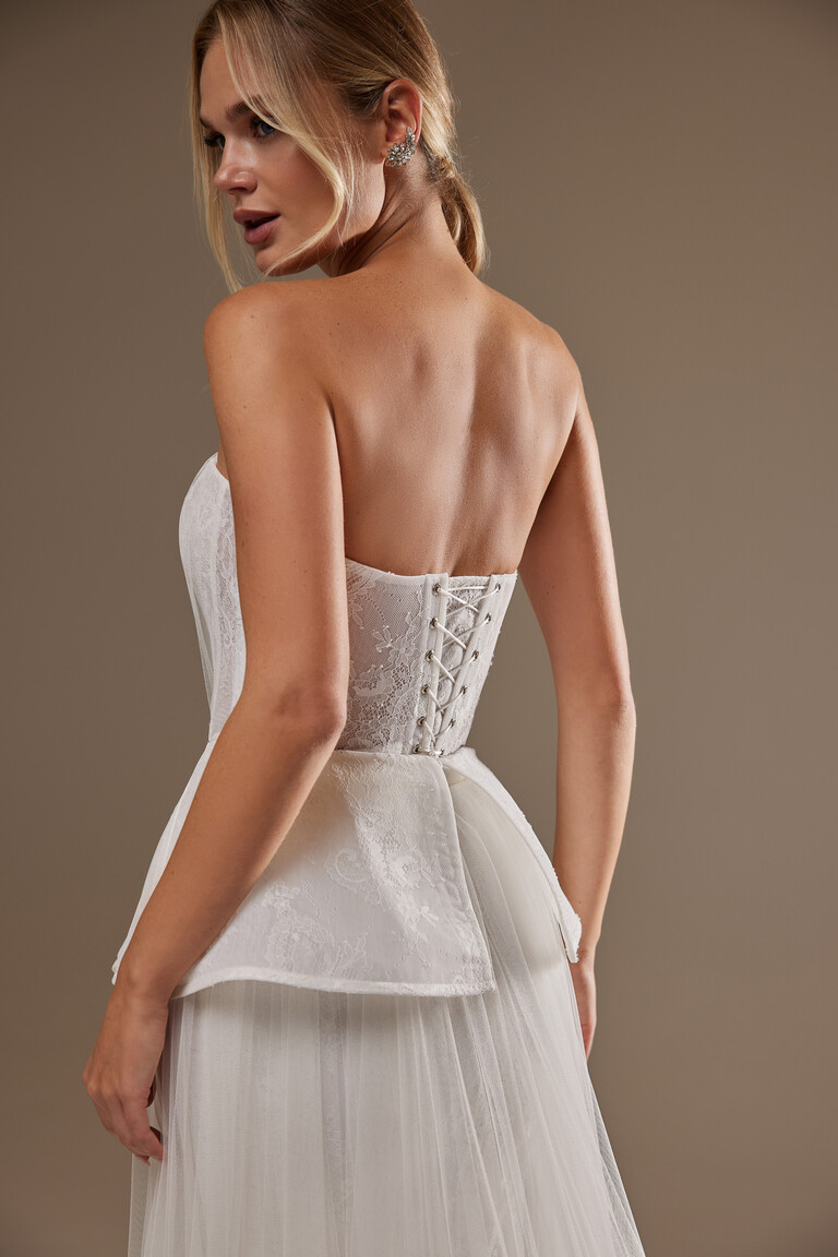 Close-up back view of Alla dress featuring lace-up corset closure and peplum detail
