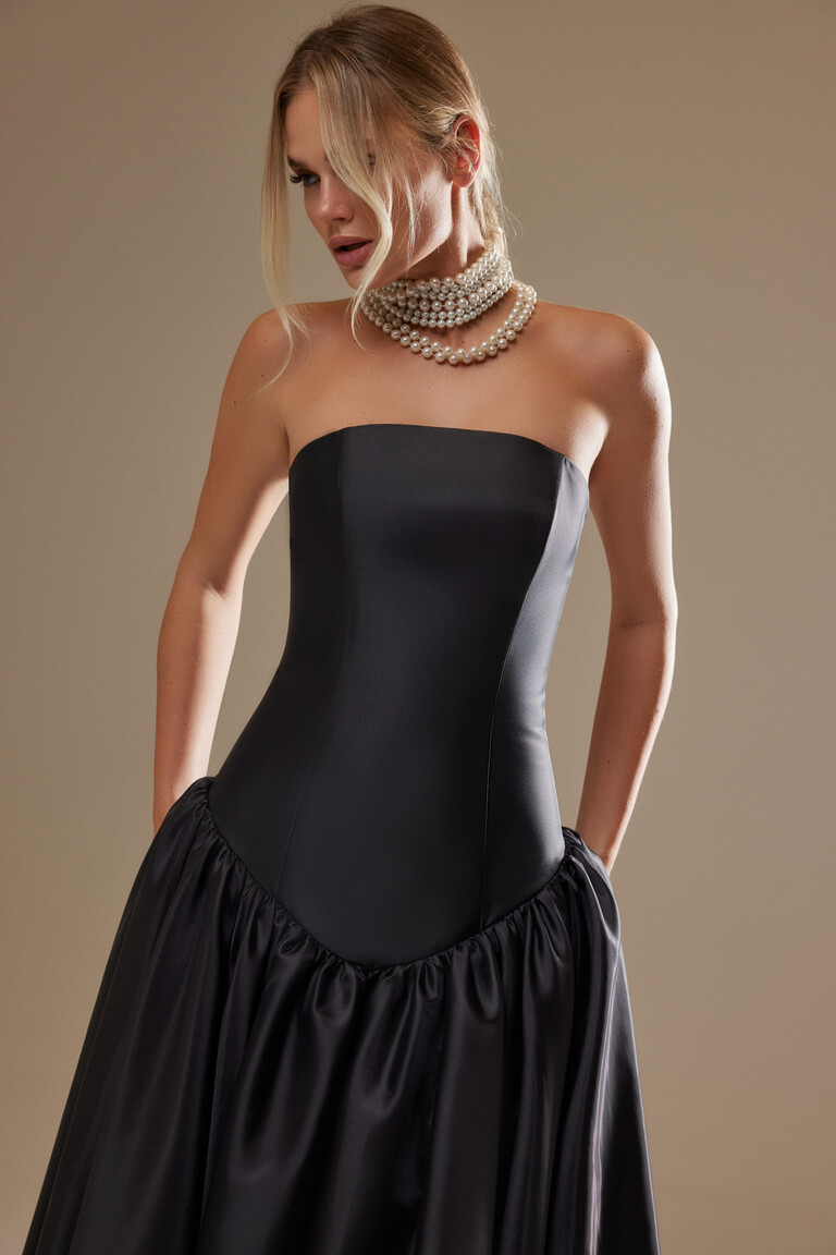Side view of the Unona Francesca black satin gown showing the structured bodice, straight neckline, and voluminous skirt.