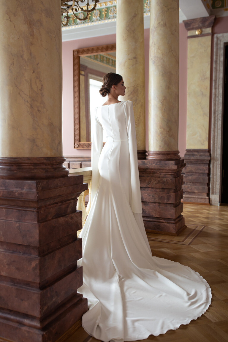 Back profile of Ashley crepe gown in classic interior showing cape sleeve movement