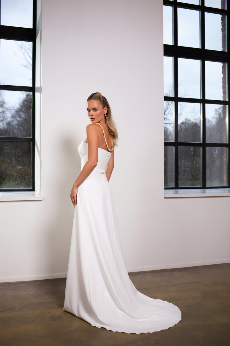 Side back view of Adeline dress featuring button details and pearl shoulder drape