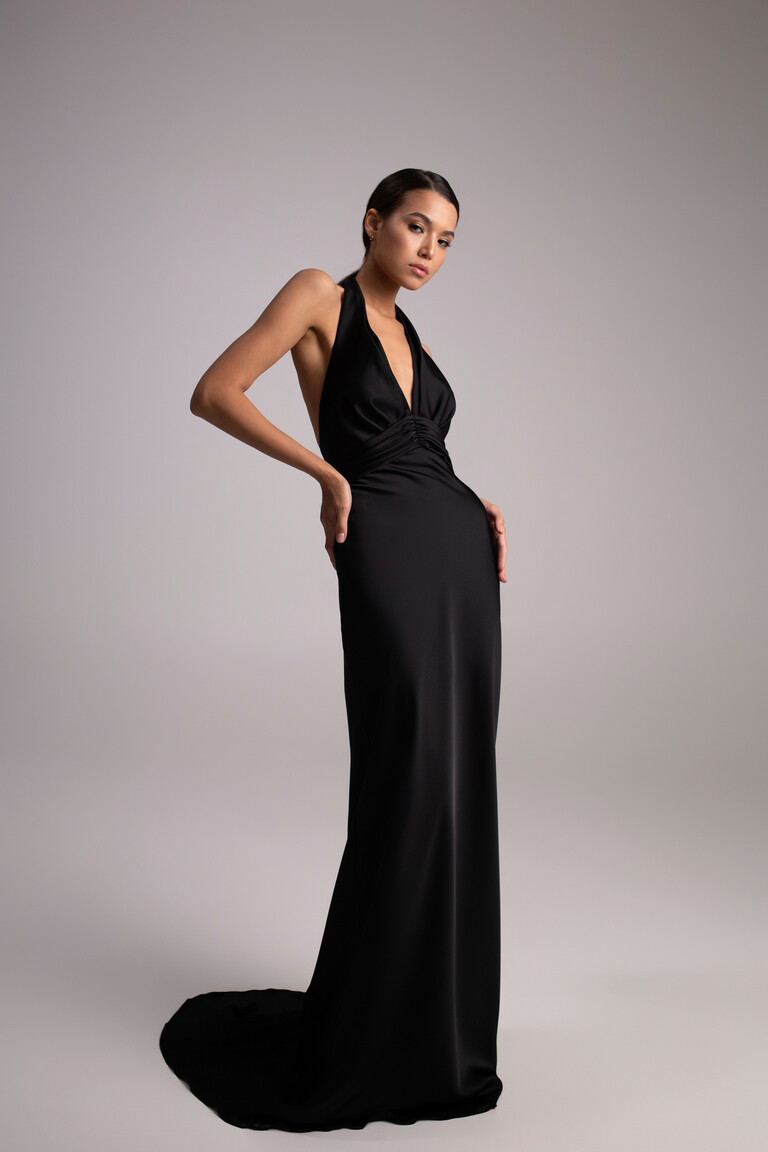 Unona Athena black silk gown with floor-length skirt and train posing with hands on hips